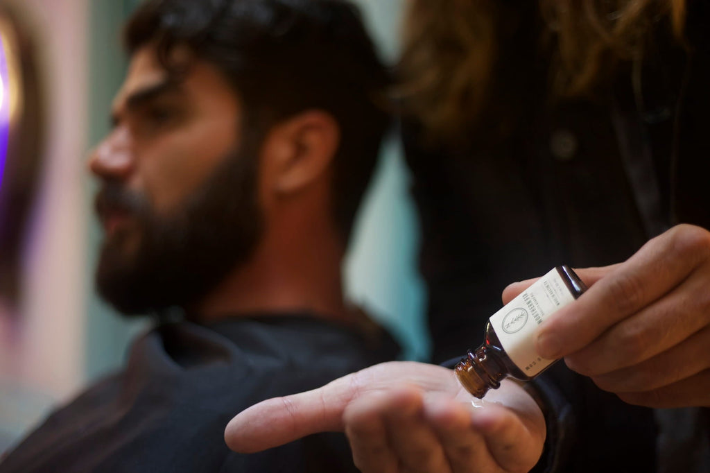 Beard oil being poured into hands to apply to a man’s beard as part of a grooming routine